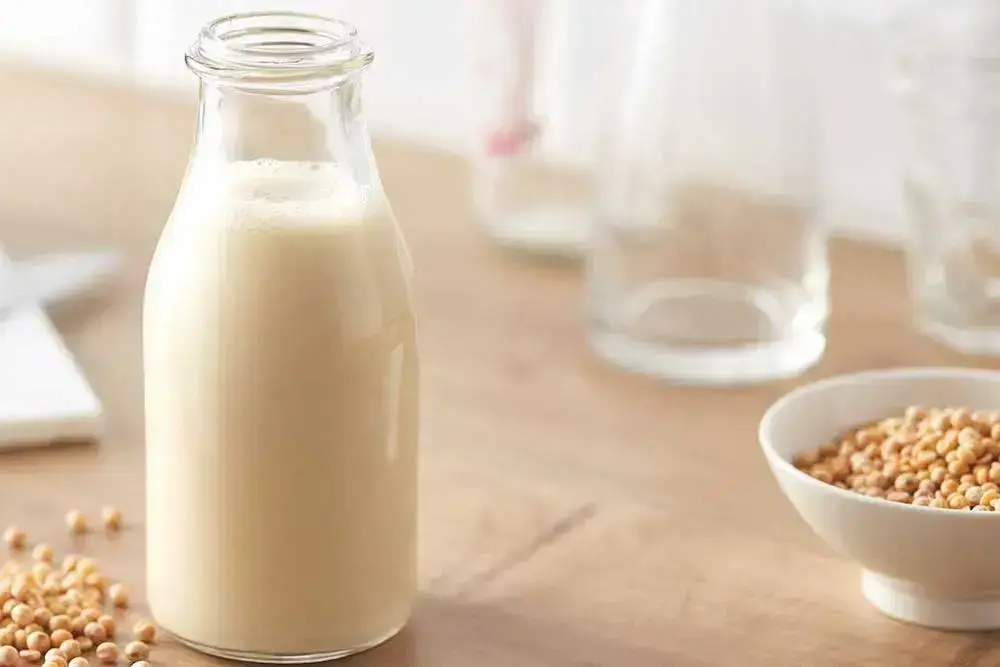 Botol susu kedelai dan biji kedelai di atas meja